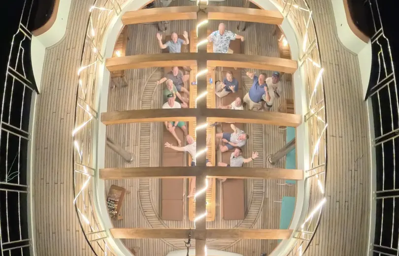 The group waving up at the camera at night from the lit deck