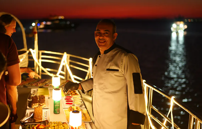 The kitchen crew at the evening buffet on deck, the sea behind them in the last light of the sunset