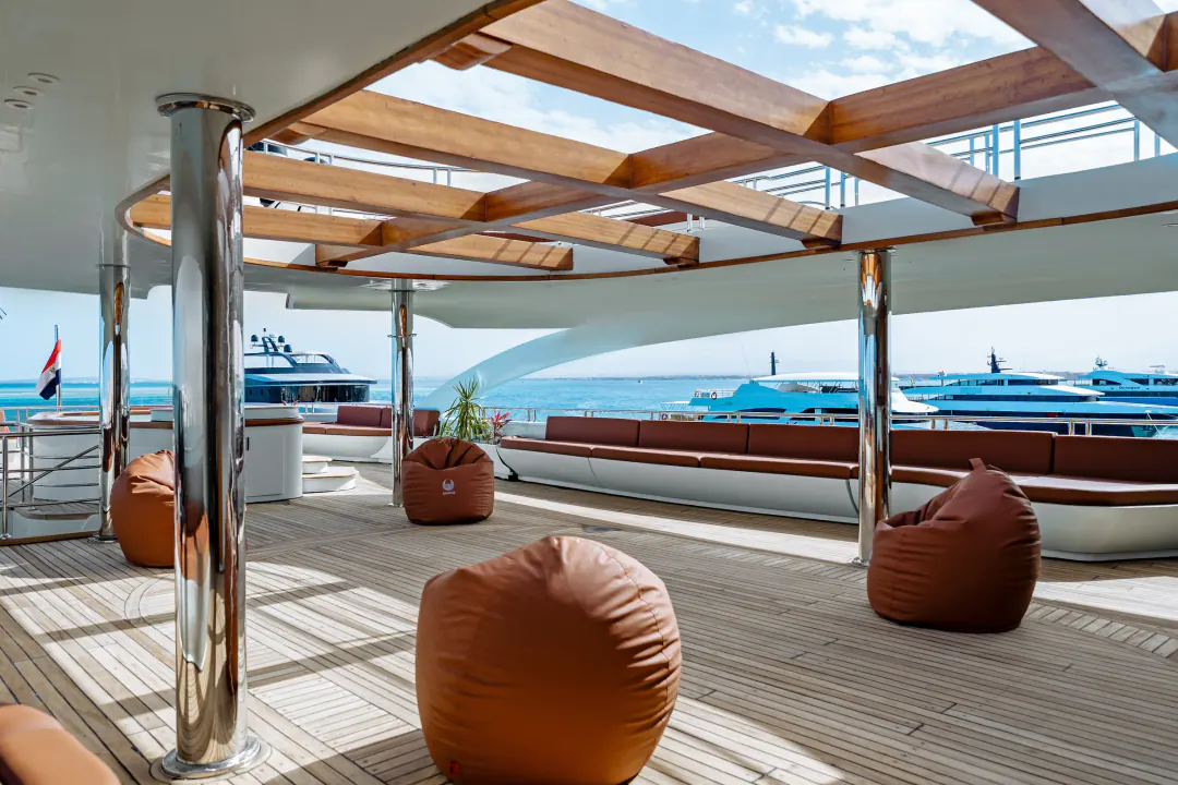 Shaded sun deck with a wooden pergola, beanbags and a view of the sea