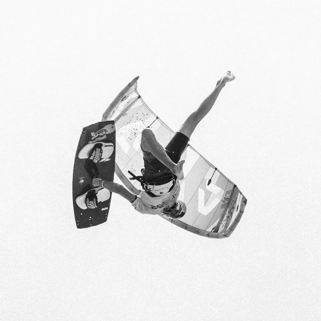 Black-and-white photo: Finn upside down high in the air, board stretched away from his feet, at the 2024 GKA event in Jericoacoara