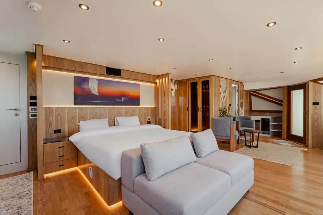 Suite with a large double bed, a sofa and a seating area, warm wood and soft lighting