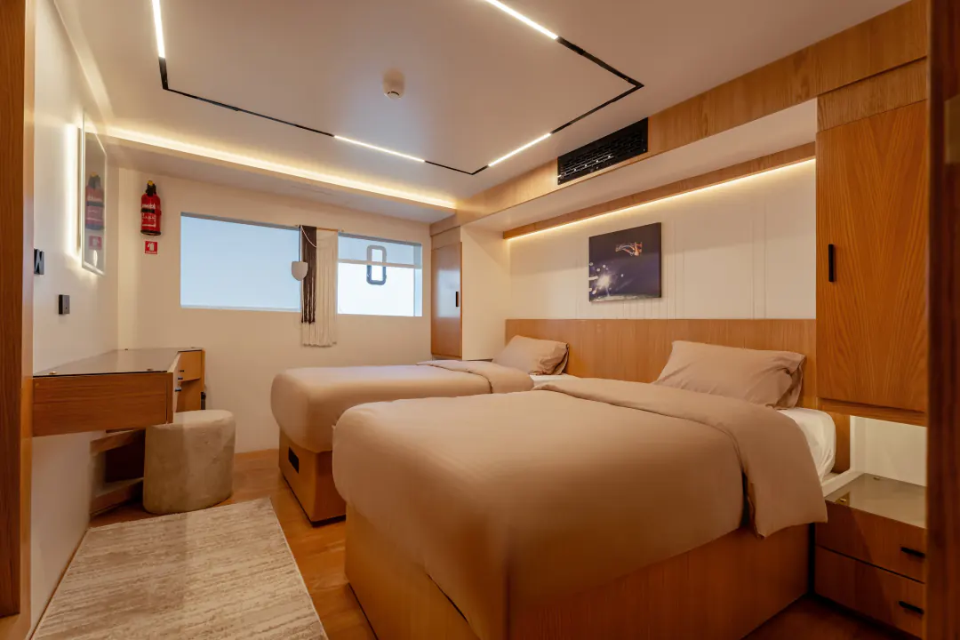 Cabin with two single beds, a desk and a window